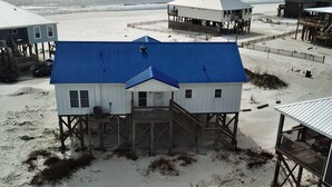 A beachside building with a blue roof, wooden deck, and a view of the ocean. - Island Time II - 102 Raphael S (Dauphin Island)