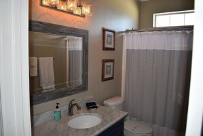 A bathroom with a large mirror, a sink, a toilet, and a shower curtain. - Island Time - 103 Treasure Ct (Dauphin Island)