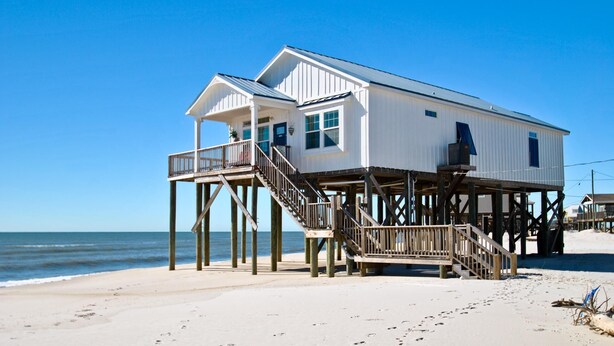 A beachfront house with a wooden deck and stairs leading to a balcony. - Island Time - 103 Treasure Ct (Dauphin Island)