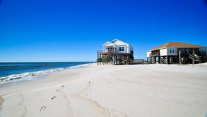 A beach with two beachfront houses, one with a balcony and the other with a staircase leading to a deck. - Island Time - 103 Treasure Ct (Dauphin Island)
