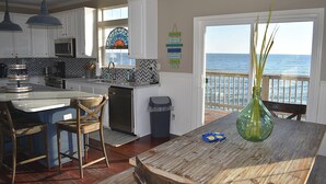 A kitchen with white cabinets, a large island, and a view of the ocean. - Island Time - 103 Treasure Ct (Dauphin Island)