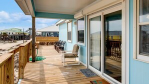 A covered deck with outdoor seating and a sliding glass door leading to a room. - Sandbar - 105 Raphael Semmes (Dauphin Island)