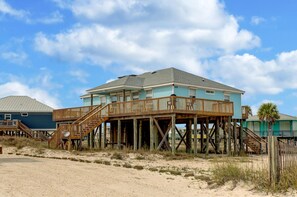 A beachfront house with a wooden deck and stairs leading to a balcony. - Sandbar - 105 Raphael Semmes (Dauphin Island)