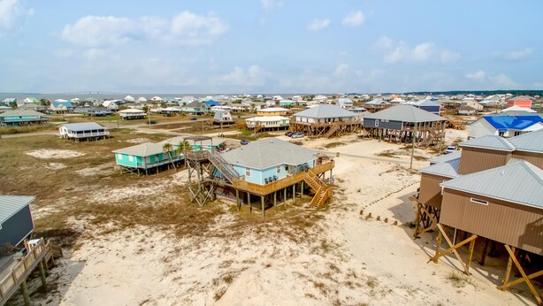 A coastal area with beach houses elevated on stilts, featuring multiple levels and outdoor decks. - Sandbar - 105 Raphael Semmes (Dauphin Island)