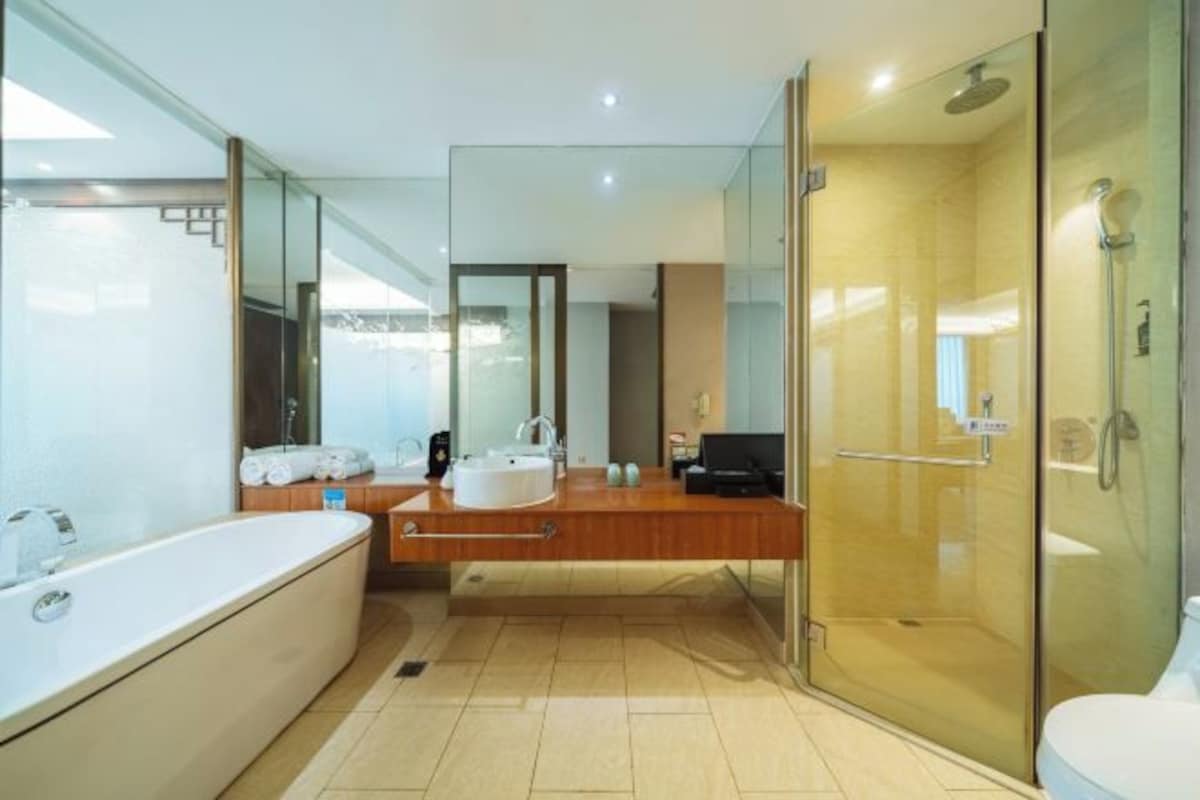 Een moderne badkamer met een glazen douchecabine, een vrijstaand bad en een wastafel met spiegel.