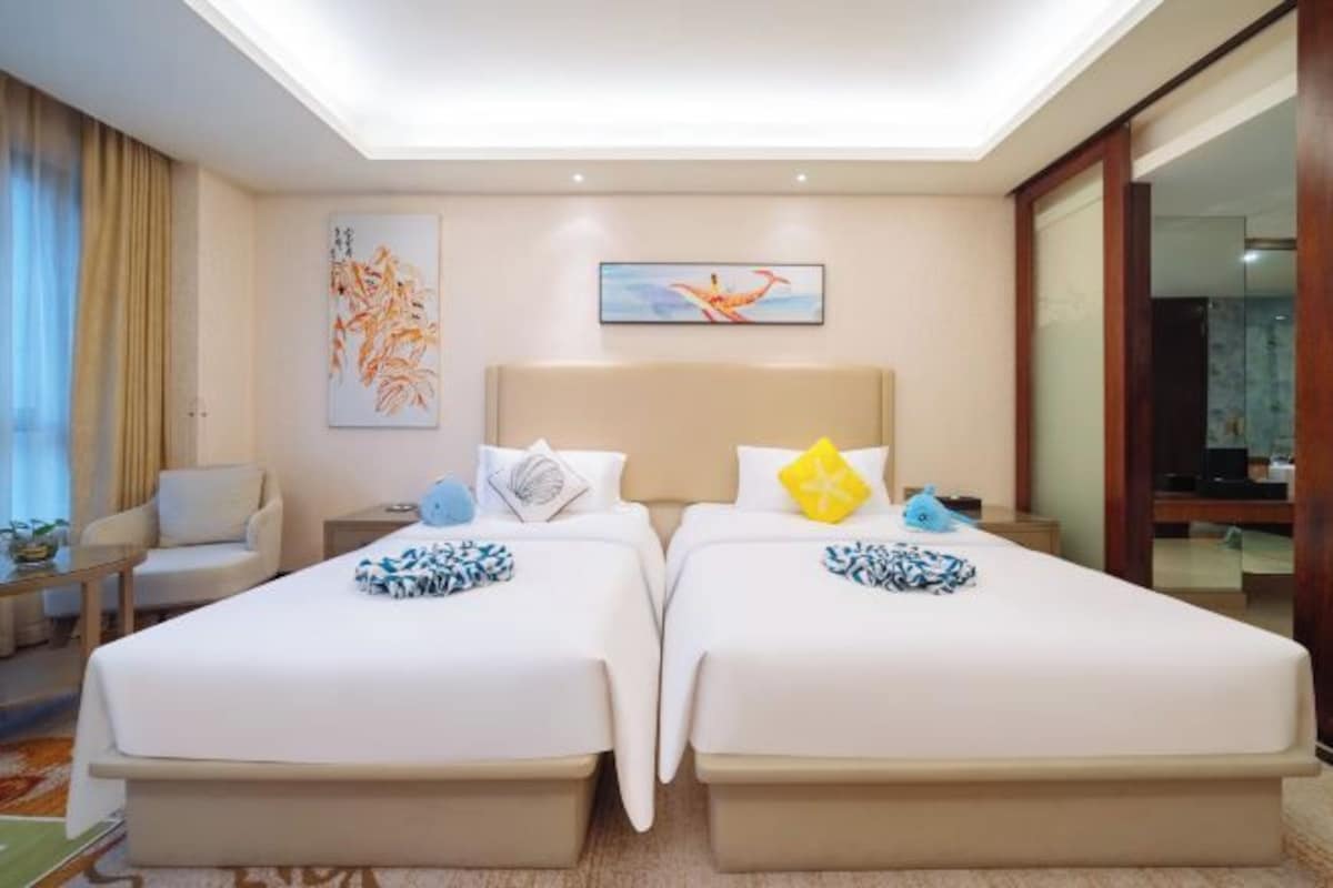 Een hotelkamer met twee bedden, een bank, een bureau en kunstwerken aan de muren.