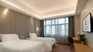 A hotel room with two beds, a desk, a chair, a TV, and a large window with curtains. - Lavande Hotels (Guangzhou)