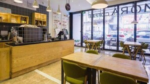 A cafe interior with a wooden counter, green chairs, and pendant lighting. - Lavande Hotels (Guangzhou)