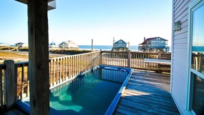 A wooden deck with a swimming pool, overlooking a beach with houses and a clear sky. - Second Wind - 2612 Bienville Blvd (Dauphin Island)
