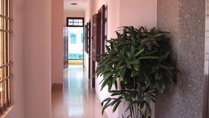 Um corredor com planta em vaso, piso de azulejos e uma porta no final.