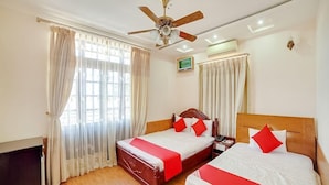 Quarto de hotel com duas camas, um ventilador de teto e uma mesa.