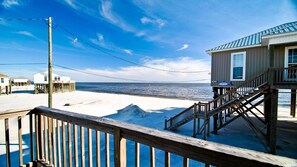 A beachside wooden structure with a staircase leading to a deck, overlooking the ocean.