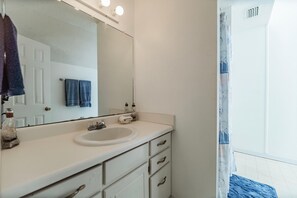 Un baño con un lavamanos blanco, un espejo y una toalla colgada en la pared.