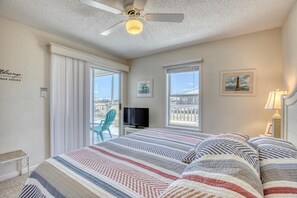 A hotel room with a bed, a television, a balcony with a chair, and a view of the ocean. - Water's Edge - 2227 Mallard (Dauphin Island)
