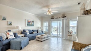 A spacious living room with a large sofa set, a small table, and a ceiling fan. - Water's Edge - 2227 Mallard (Dauphin Island)