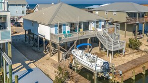 A waterfront property with elevated houses, a dock, and a boat. - Water's Edge - 2227 Mallard (Dauphin Island)