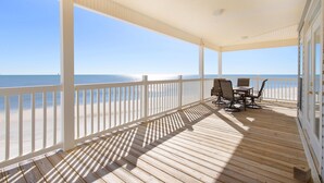 A covered deck with a view of the beach, wooden flooring, and a table with chairs. - Simple Pleasures - 103 Strand (Dauphin Island)