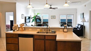 A modern kitchen with a large island, double sink, and a view of the ocean. - West Beach - 104 Westward Ho (Dauphin Island)