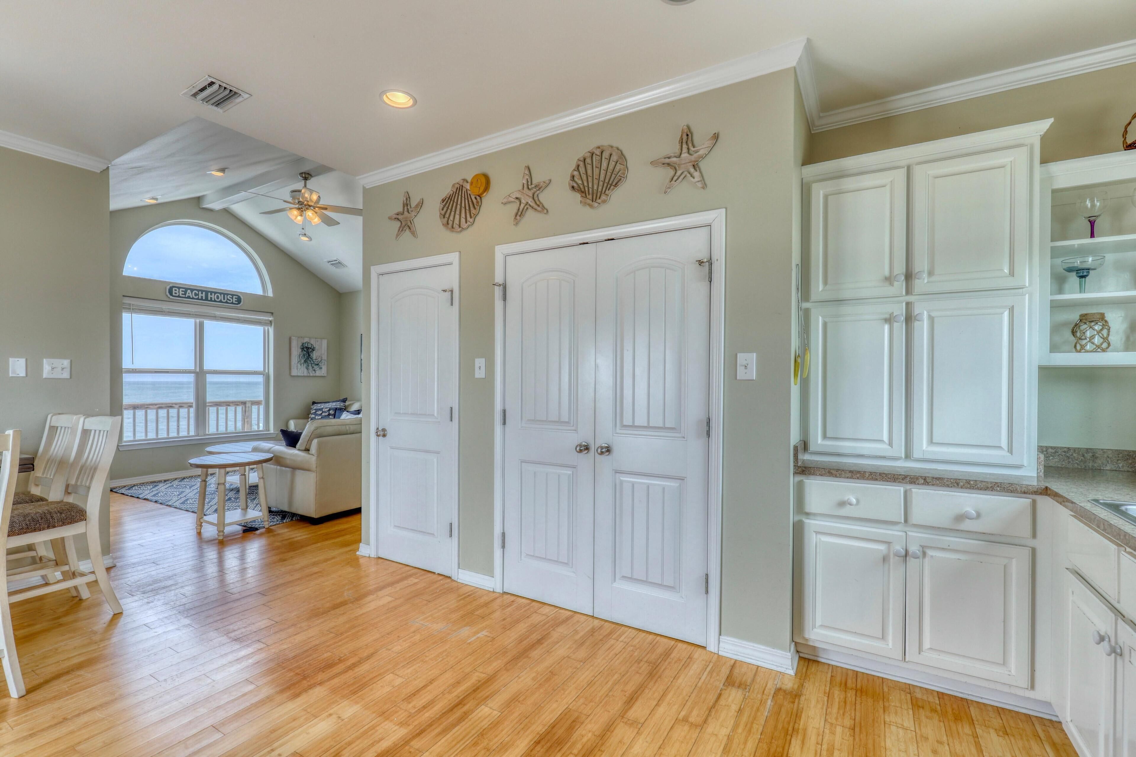 A spacious room with a wooden floor, white doors, and a kitchen area with white cabinets.