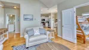 A modern living room with a sofa, coffee table, and a staircase leading to a loft bedroom. - Villa Delphinus - 103 Vargus C (Dauphin Island)