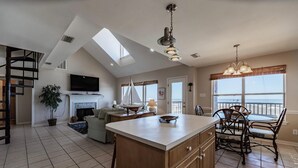 A spacious kitchen with a large island, a dining area with a view, and a fireplace. - Tropical Paradise - 2354 Islan (Dauphin Island)