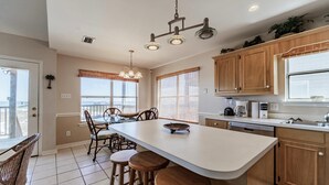 A kitchen with a large island, wooden cabinets, and a view to the outside. - Tropical Paradise - 2354 Islan (Dauphin Island)
