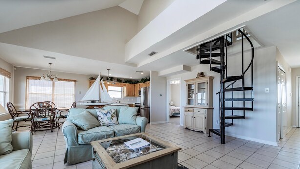 A spacious living area with a sofa, coffee table, and a spiral staircase. - Tropical Paradise - 2354 Islan (Dauphin Island)