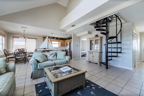 A spacious living area with a sofa, coffee table, and a spiral staircase. - Tropical Paradise - 2354 Islan (Dauphin Island)