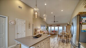 A spacious kitchen with a large island, pendant lights, and a view to the living area. - Rainbows End - 100-b Shell Ct (Dauphin Island)