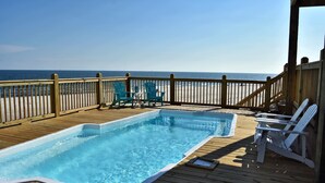 A wooden deck with a hot tub and two chairs, overlooking a beach. - Island Time IV - 101 Pushmatah (Dauphin Island)