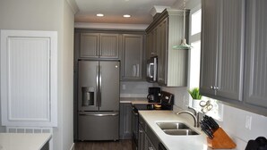 A compact kitchen with grey cabinetry, stainless steel appliances, and a white countertop. - Island Time IV - 101 Pushmatah (Dauphin Island)