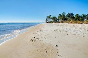 Une plage de sable avec des empreintes et un ciel bleu dégagé.