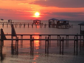 A pier extending into calm waters with a sunset in the background.