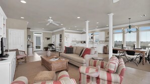 A spacious living room with a sofa, chairs, a coffee table, and a dining area with a table and chairs. - Tramarlis - 2254 Sandpiper (Dauphin Island)