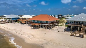 A beachfront property with elevated wooden structures, a sandy beach, and a view of the ocean.