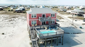 A two-story beachfront house with a pool on the second level.