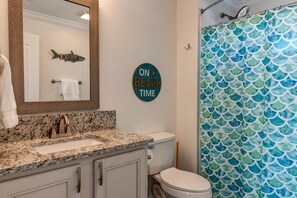 A bathroom with a sink, toilet, and a shower curtain with a fish scale pattern.