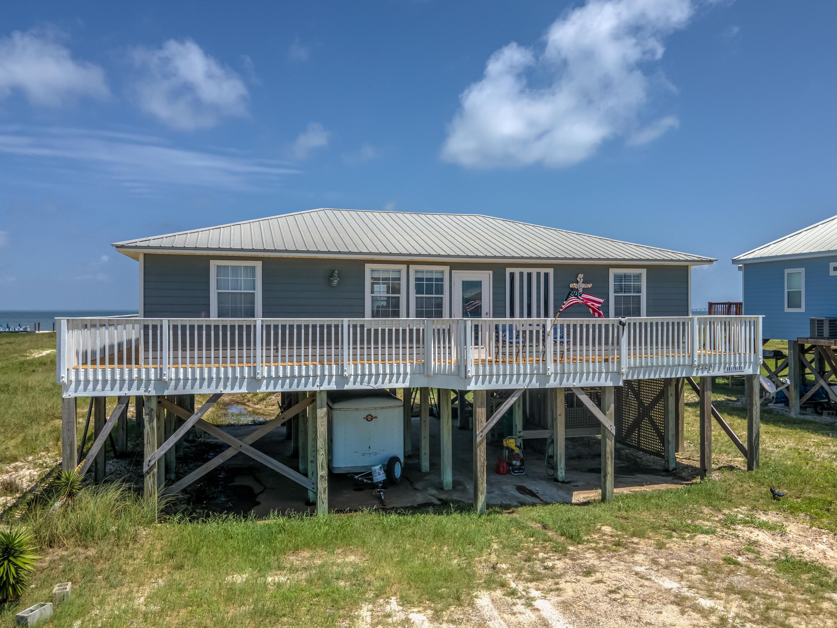 A beach house with a deck, a small shed, and a flag.