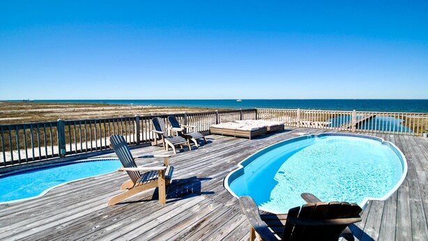 A wooden deck with a pool, lounge chairs, and a view of the ocean. - Tidal Wave - 2636 Bienville (Dauphin Island)