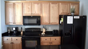 Una cocina con armarios de madera, un microondas negro, una estufa, un refrigerador y un tostador.