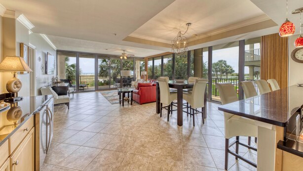 A spacious kitchen with a dining area, large windows, and a balcony. - Holiday Isle #122 (Dauphin Island)