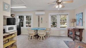 A compact kitchen with a dining table, chairs, a microwave, and a refrigerator. - Surf Shack - 1013 Cadillac (Dauphin Island)