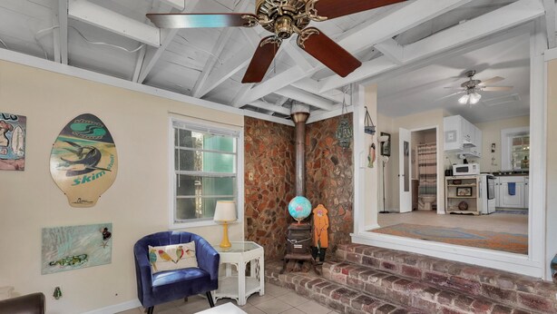 A spacious living area with a blue armchair, a white coffee table, and a stone wall. - Surf Shack - 1013 Cadillac (Dauphin Island)