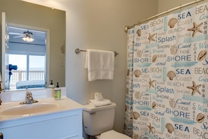 A bathroom with a white sink, a toilet, and a shower curtain with sea-themed words.