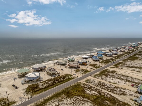 An aerial view of a coastal area with buildings along the shoreline, a road, and the ocean.