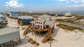 Una propiedad frente a la playa con varias casas, un edificio central con terraza y una playa de arena.