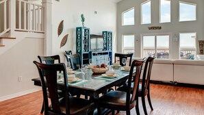 Un comedor con una mesa de madera, sillas y una cocina al fondo.