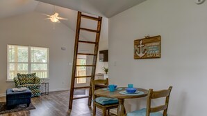 Un comedor con una mesa de madera, sillas y una escalera apoyada en la pared.