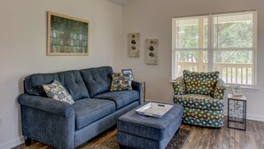 Una sala de estar con un sofá azul, un sillón estampado y una mesita con una bandeja.