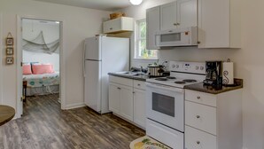Una cocina funcional con armarios blancos, microondas, estufa y pileta.